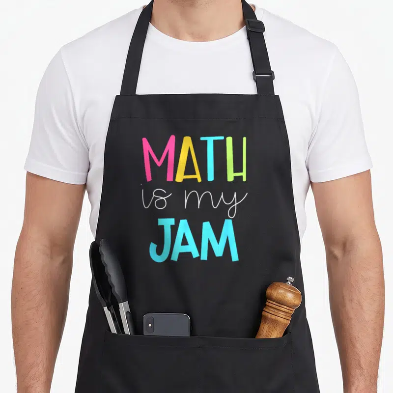 Jam teacher apron - Stacked text MATH is my JAM in pink yellow blue green and white lettering — shown on a black cotton canvas apron against a white background