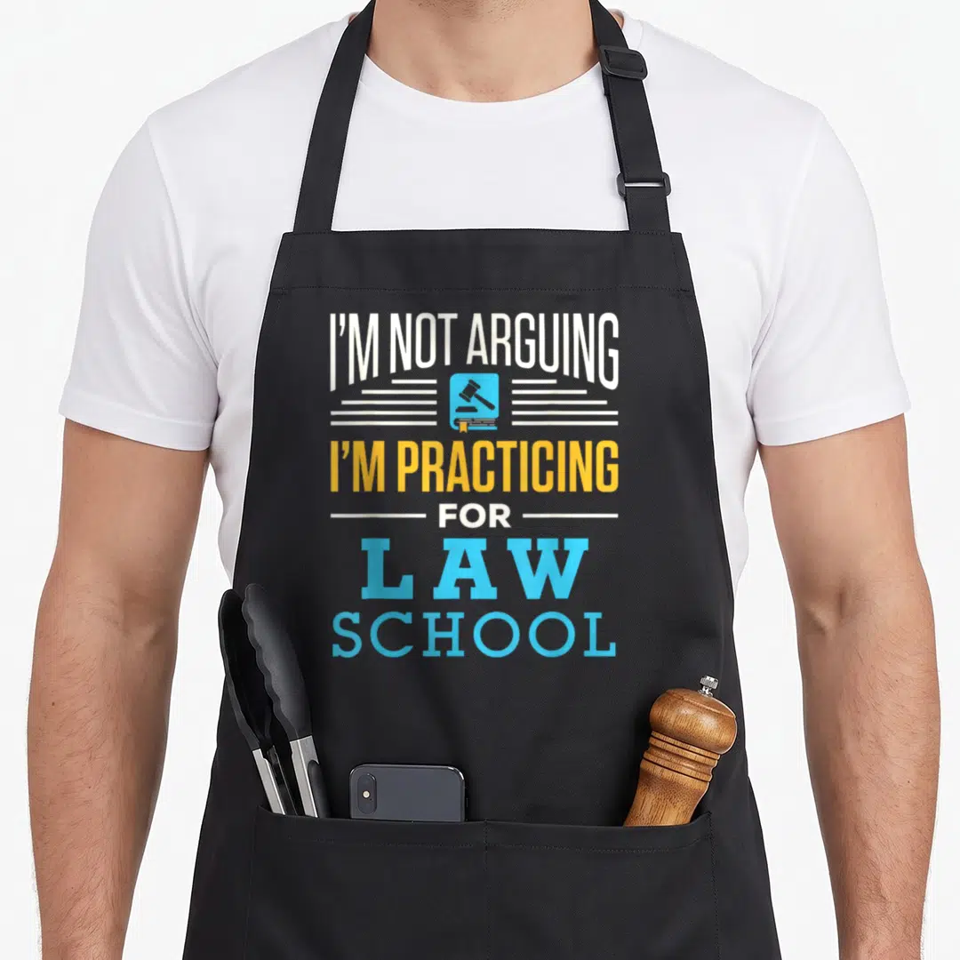 Arguing lawyer apron - Stacked text I'M NOT ARGUING I'M PRACTICING FOR LAW SCHOOL with gavel icon on book — shown on a black cotton canvas apron against a white background