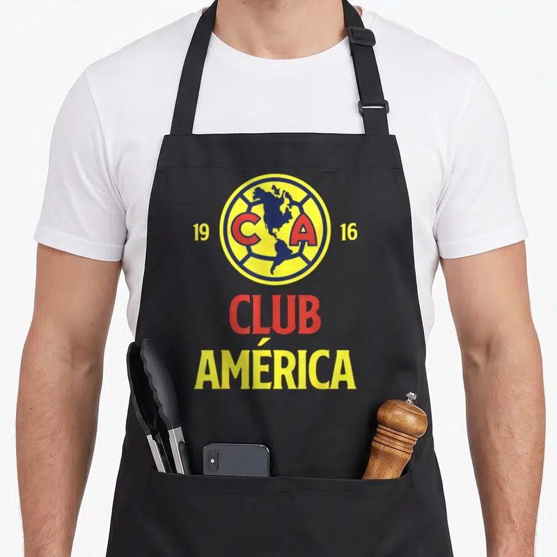Our exclusive collection apron - Club América logo with map, 1916 dates, and red yellow blue text — shown on a black cotton canvas apron against a white background