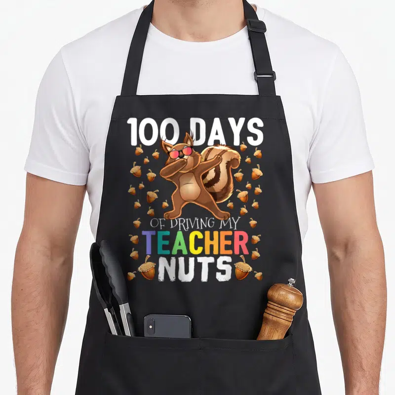 Driving squirrel aprons - Dabbing squirrel with sunglasses and acorns surrounding text 100 DAYS OF DRIVING MY TEACHER — shown on a black cotton canvas apron against a white background
