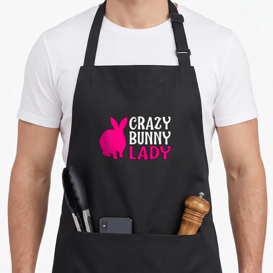 Hare animal bunny apron - Pink rabbit silhouette beside stacked white and pink Crazy Bunny Lady text — shown on a black cotton canvas apron against a white background