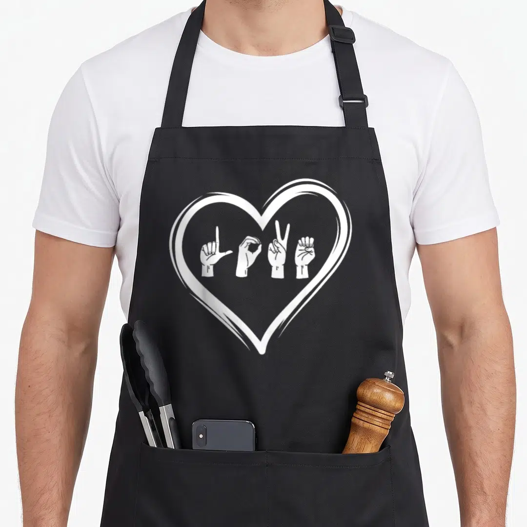 Interpreter teacher apron - White heart outline enclosing four hand signs in line art style — shown on a black cotton canvas apron against a white background