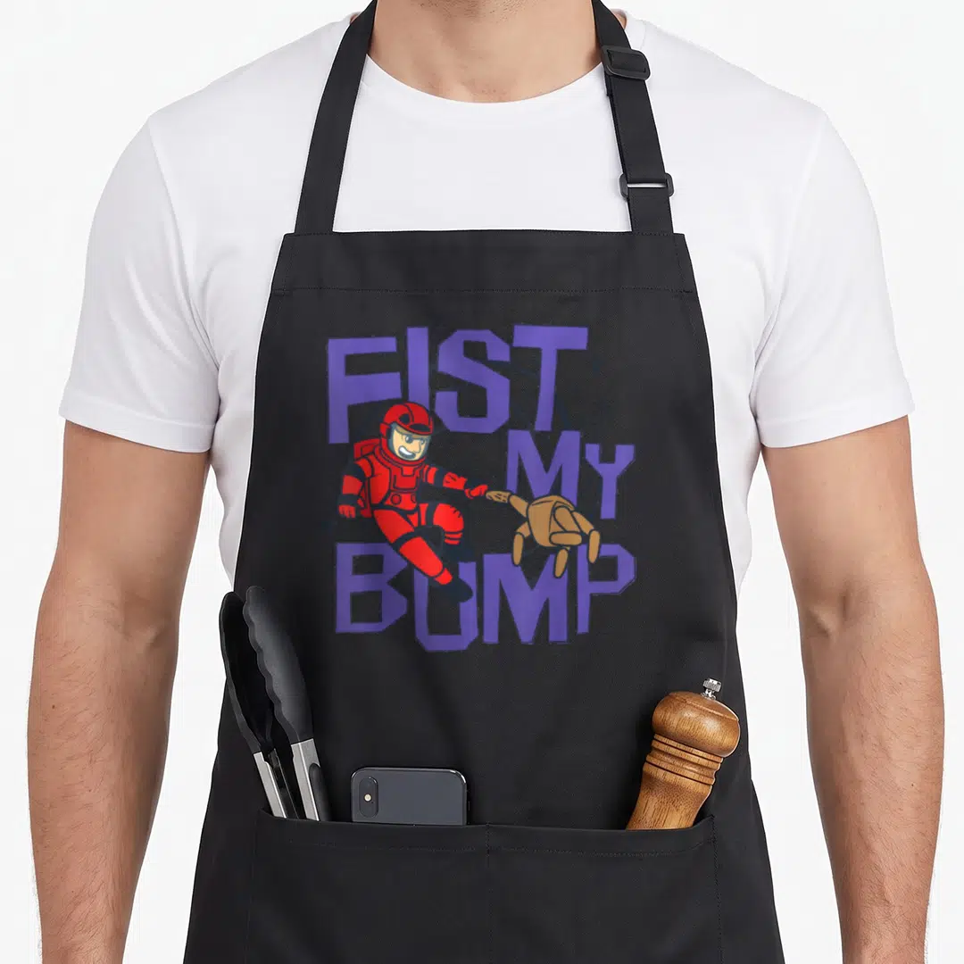 Funny fist bump apron - Astronaut in red suit fist-bumps tan hand among purple stacked text and stars — shown on a black cotton canvas apron against a white background