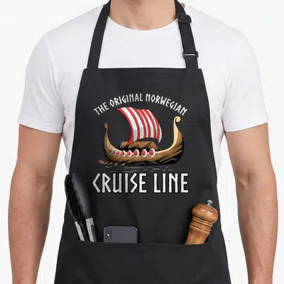 Cruise norwegian kitchen aprons - Cartoon viking ship with red and white sail and arched text reading THE ORIGINAL — shown on a black cotton canvas apron against a white background