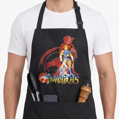 Funny lion apron - Lion-O holding sword with red halftone silhouette and THUNDERCATS logo in cartoon style — shown on a black cotton canvas apron against a white background