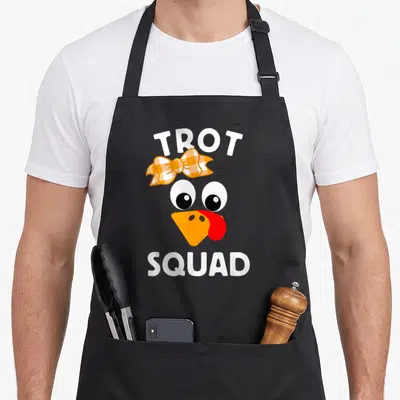 Running thanksgiving day aprons - Cartoon turkey head with orange plaid bow and white TROT SQUAD text — shown on a black cotton canvas apron against a white background