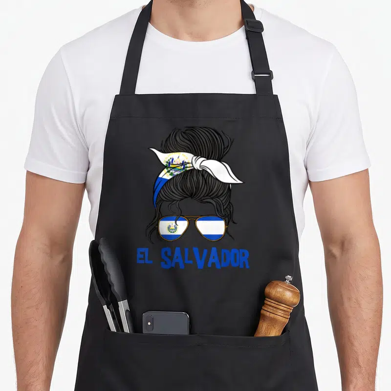 Flag salvadoran apron - Black hair bun with sunglasses and headband printed with El Salvador flag and blue text below — shown on a black cotton canvas apron against a white background