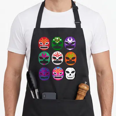 Lucha wrestling apron - Nine colorful lucha libre masks in 3x3 grid with cartoon art in red green purple orange blue — shown on a black cotton canvas apron against a white background