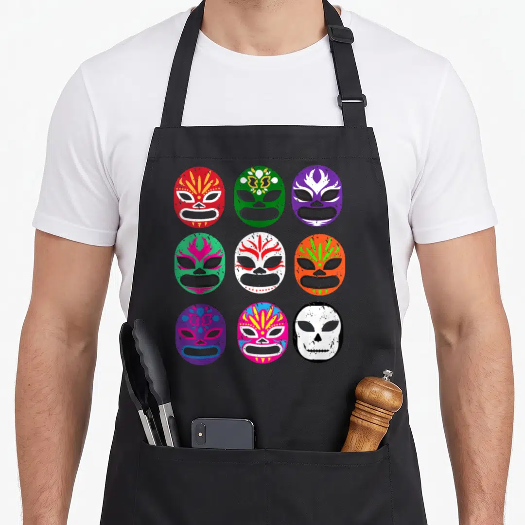 Lucha wrestling apron - Nine colorful lucha libre masks in 3x3 grid with cartoon art in red green purple orange blue — shown on a black cotton canvas apron against a white background
