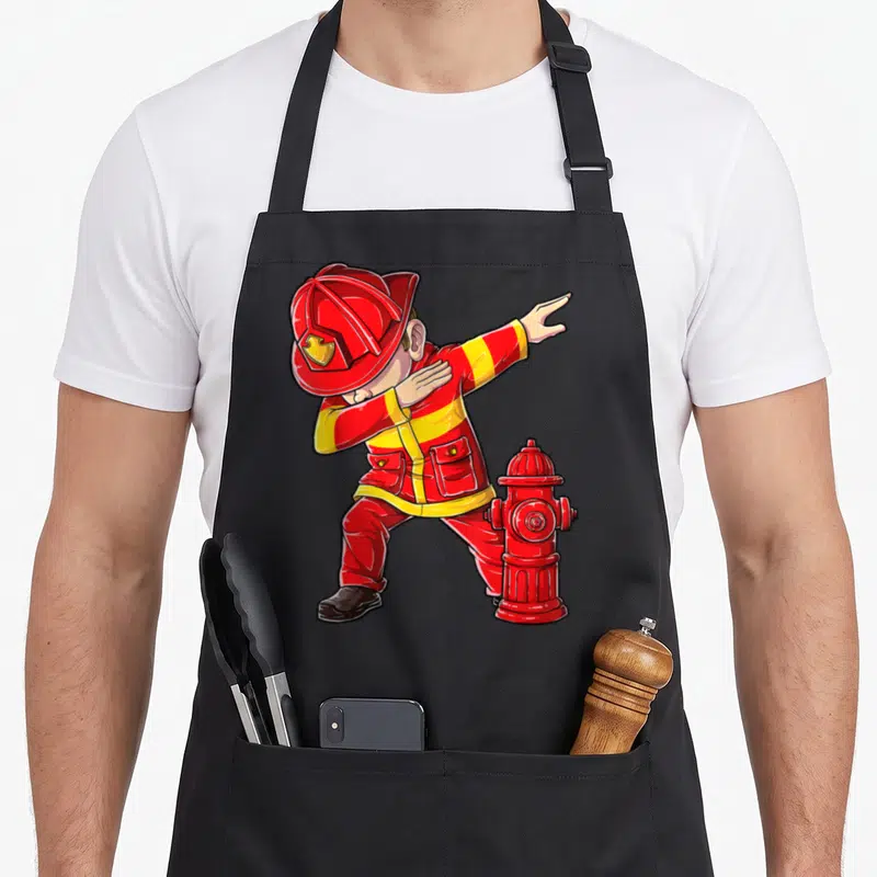 Dabbing firefighter apron - Cartoon fireman dabbing pose with red hydrant in red and yellow graphic art style — shown on a black cotton canvas apron against a white background