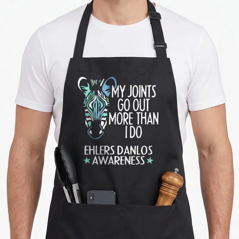 Ehler i love my zebra apron - Colorful zebra head with My Joints Go Out More Than I Do text and Ehlers Danlos Awareness — shown on a black cotton canvas apron against a white background