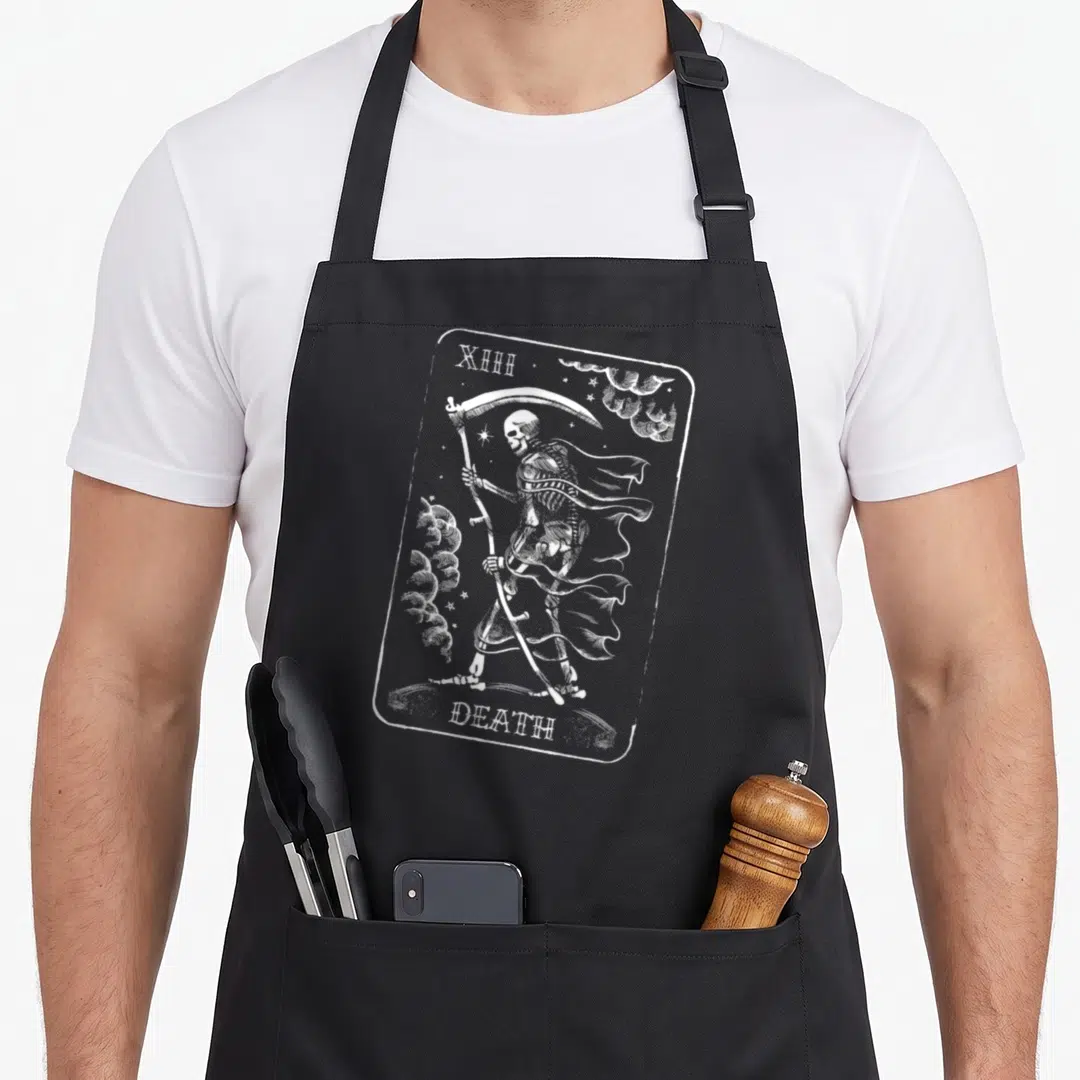 Gasp halloween apron - White line-art skeleton holding scythe inside rounded frame with text XIII and DEATH — shown on a black cotton canvas apron against a white background
