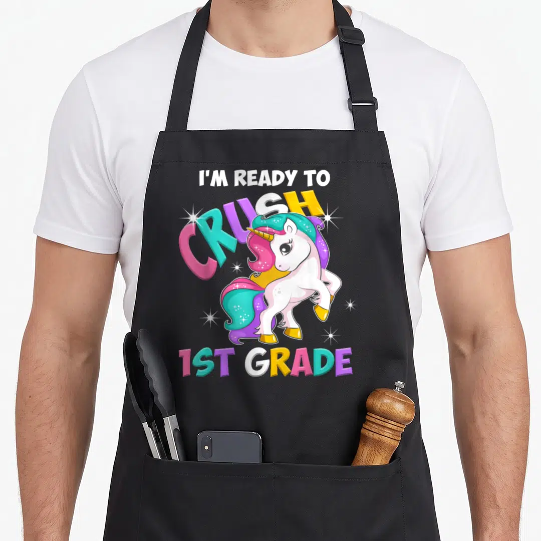 Grade unicorn apron - Cartoon unicorn with multicolored mane and text I'm Ready to Crush 1st Grade — shown on a black cotton canvas apron against a white background