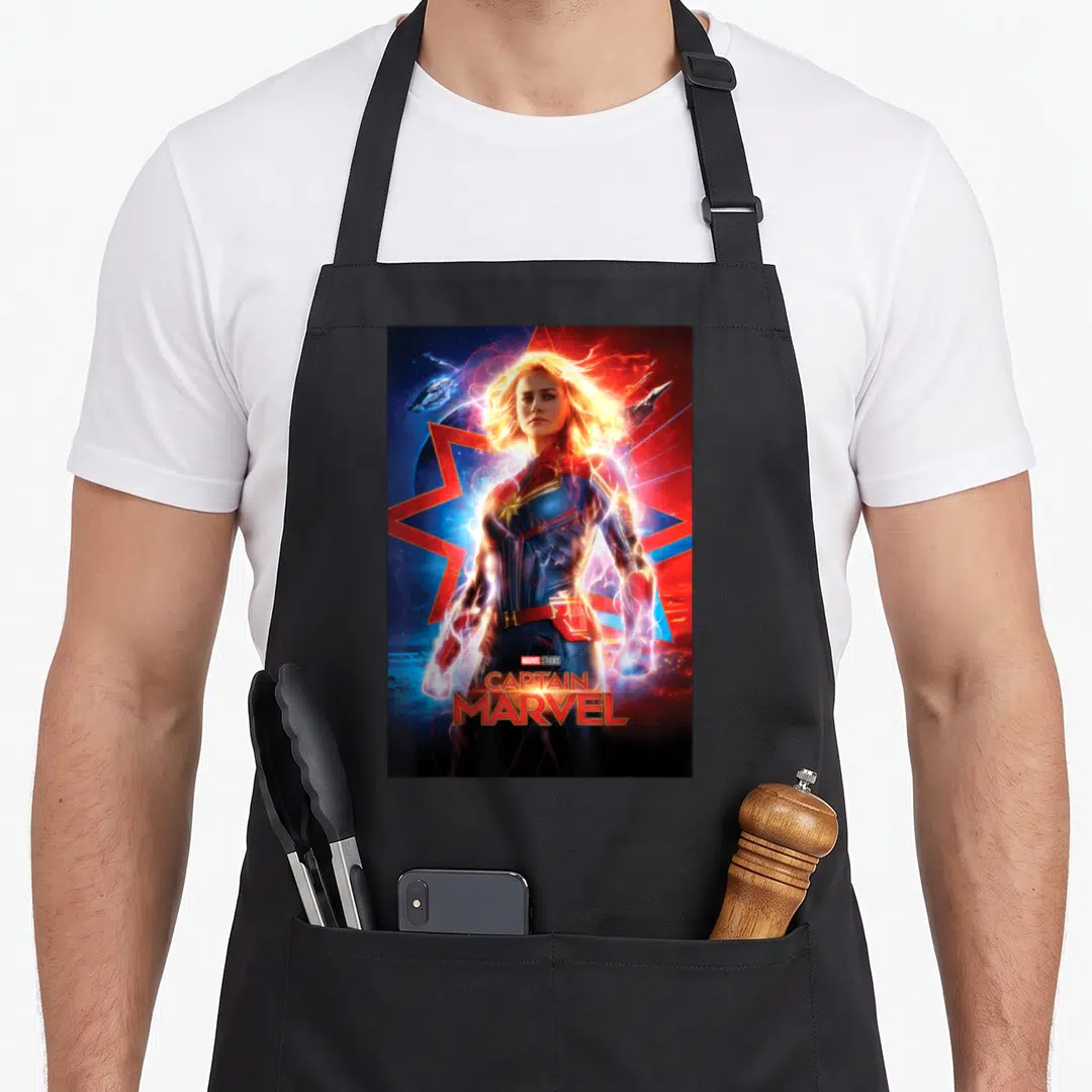 Suited captain apron - Photo-style Captain Marvel with red blue gold star and stacked text logo — shown on a black cotton canvas apron against a white background