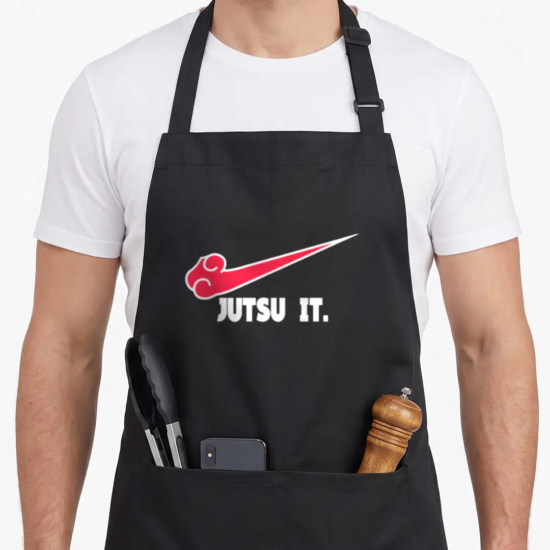 Jutsu jiu apron - Red cloud swoosh shape above white JUTSU IT text on grey background — shown on a black cotton canvas apron against a white background