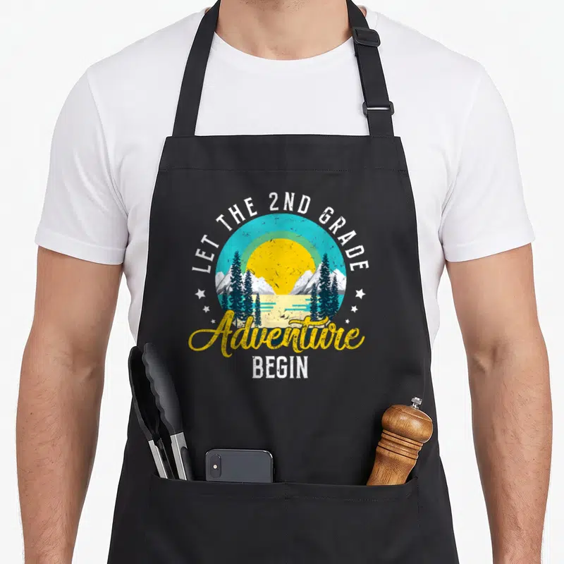 Jrw1 2nd apron - Retro circular landscape with yellow sun, blue mountains, teal trees, and white stars surrounding — shown on a black cotton canvas apron against a white background