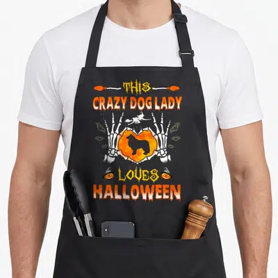 Halloween border collie apron - Skeleton hands holding heart with dog silhouette and witch flying above Halloween text — shown on a black cotton canvas apron against a white background