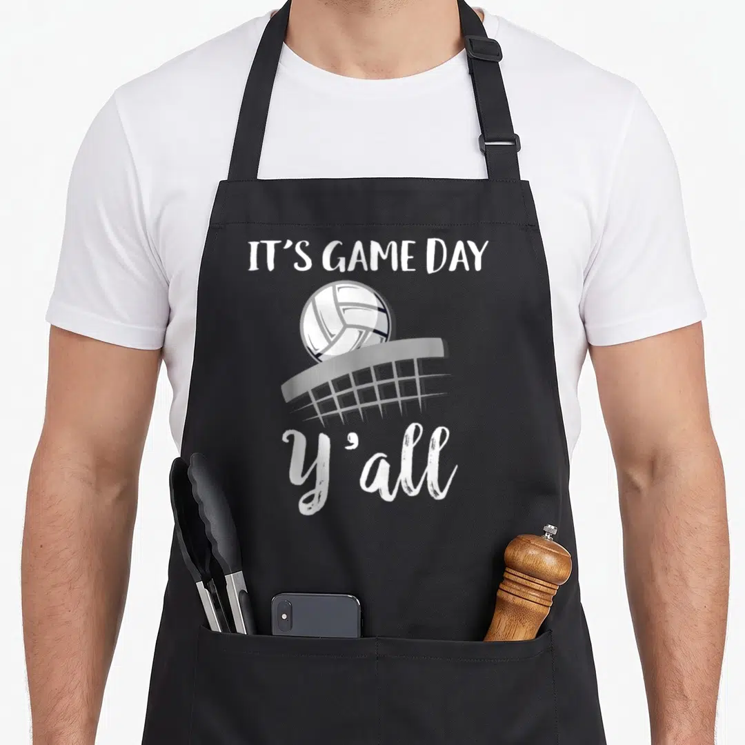Yall game aprons - White IT'S GAME DAY text, volleyball, grey net, and Y'all script on grey background — shown on a black cotton canvas apron against a white background