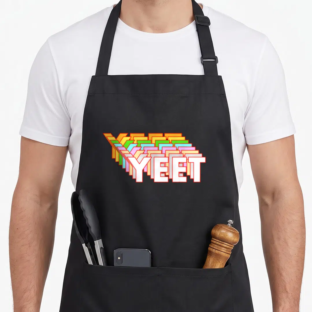 Yeet video game apron - Diagonal stack of YEET text in white orange green blue pink colors — shown on a black cotton canvas apron against a white background