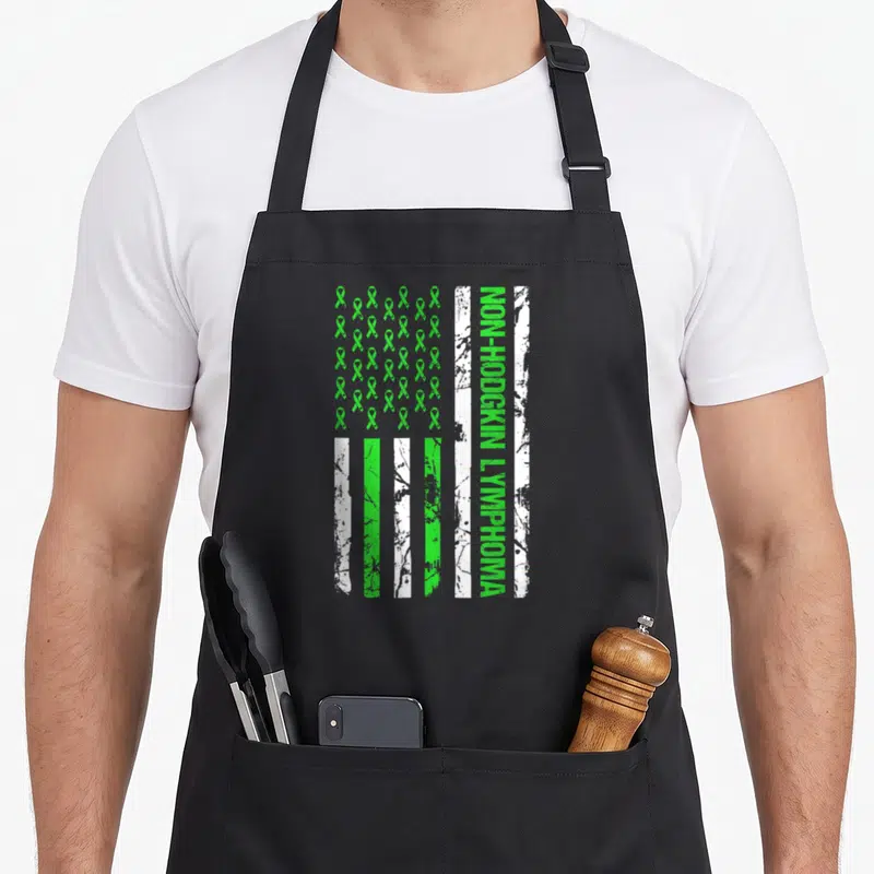Flag lime green apron - Distressed flag print with grid of green ribbons and vertical Non-Hodgkin Lymphoma text — shown on a black cotton canvas apron against a white background