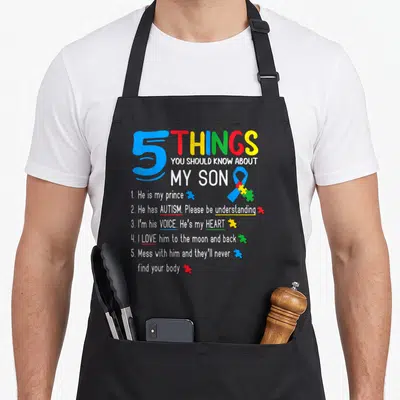 Autistic dad and son aprons - Colorful text listing 5 things about an autistic son with a blue ribbon and puzzle pieces — shown on a black cotton canvas apron against a white background