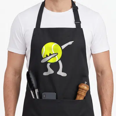 Dabbing tennis apron - Cartoon yellow tennis ball with grey limbs performing a dab dance move — shown on a black cotton canvas apron against a white background