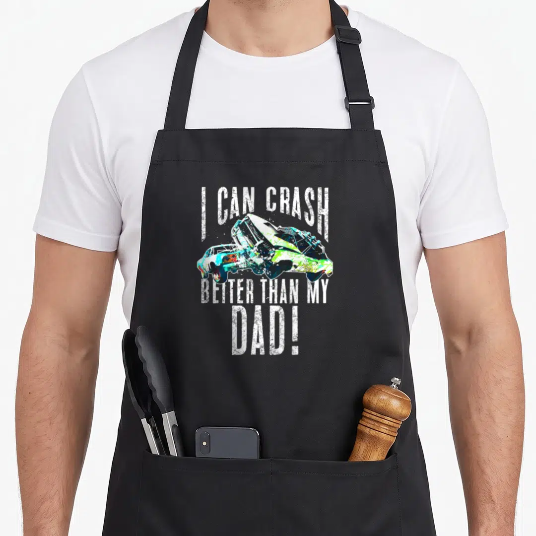 Crash demolition derby apron - Two crashing cars with distressed text I CAN CRASH BETTER THAN MY DAD in white, blue — shown on a black cotton canvas apron against a white background
