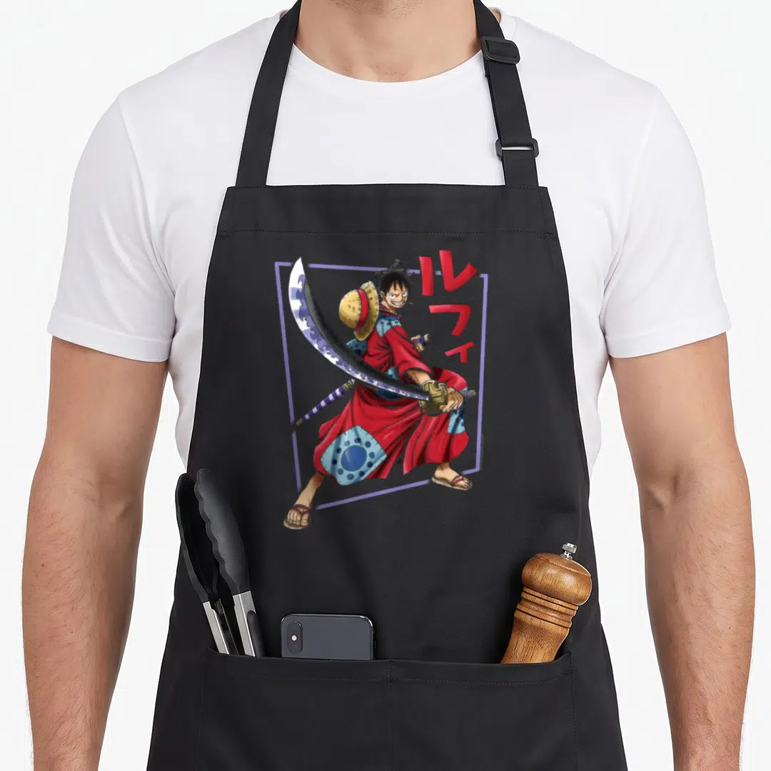 Wano anime apron - Man in red kimono holding sword with red katakana text and purple frame — shown on a black cotton canvas apron against a white background