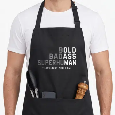 Gag father day apron - Distressed white text reading OLD ASS MAN stacked vertically with centered tagline below — shown on a black cotton canvas apron against a white background