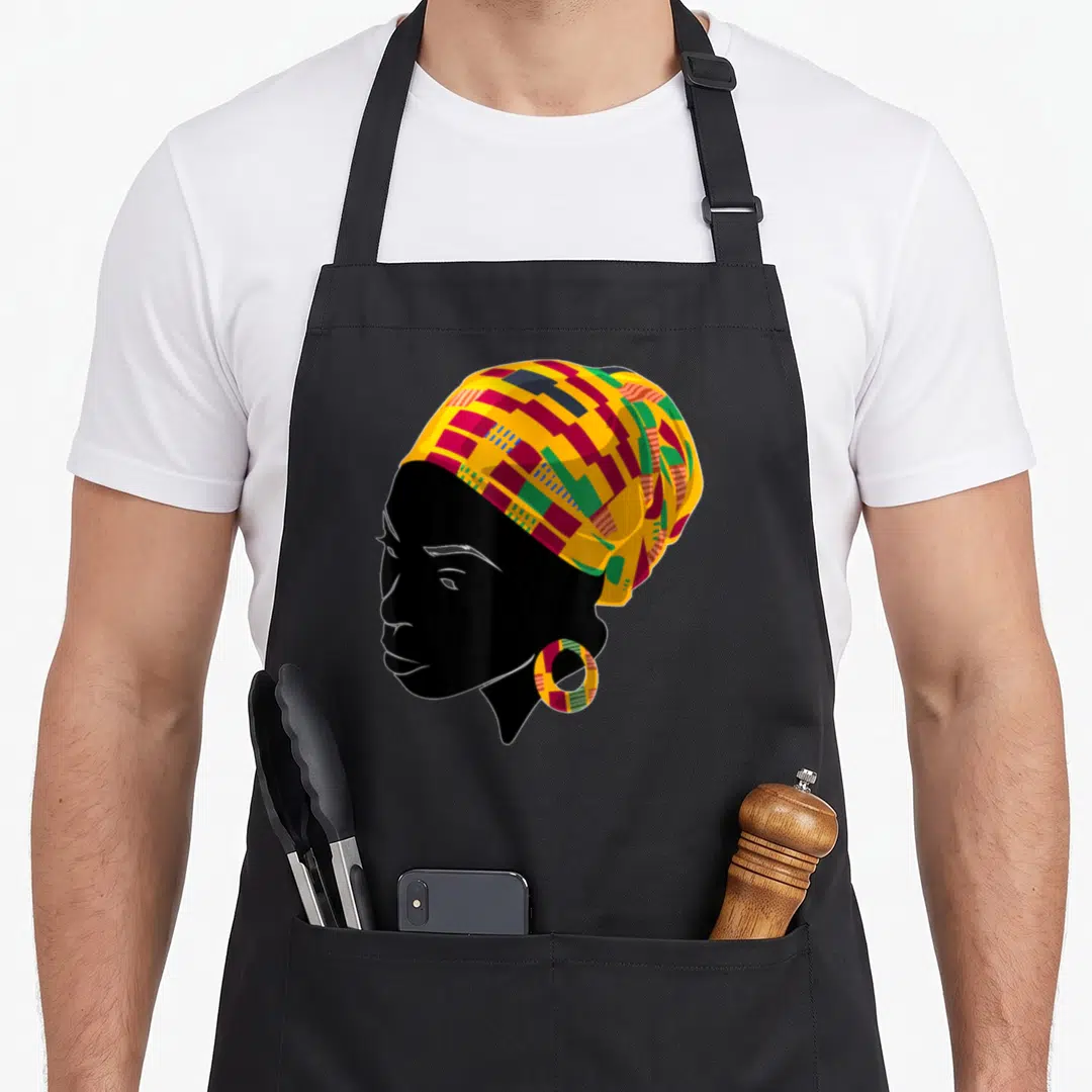 Kente african apron - Black silhouette woman profile with yellow red green patterned headwrap and matching hoop earring — shown on a black cotton canvas apron against a white background
