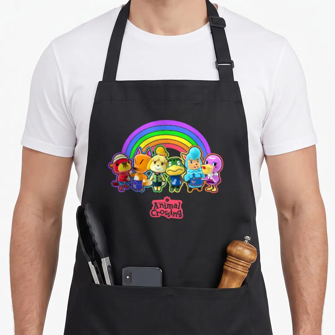 Rainbow line apron - Six cartoon animals under a rainbow arch with Animal Crossing text logo — shown on a black cotton canvas apron against a white background
