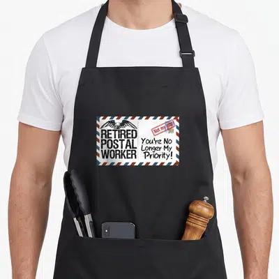 Postal retirement apron - Envelope design with eagle, 'Retired Postal Worker' text, and red Not my job stamp — shown on a black cotton canvas apron against a white background