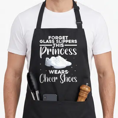 Vintage cheerleader cheerleading apron - White cheer shoes and text forget glass slippers this princess wears cheer — shown on a black cotton canvas apron against a white background
