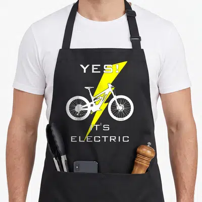 Ebike mtb bicycle apron - White bicycle silhouette with yellow lightning bolt and Yes Its Electric text on grey — shown on a black cotton canvas apron against a white background