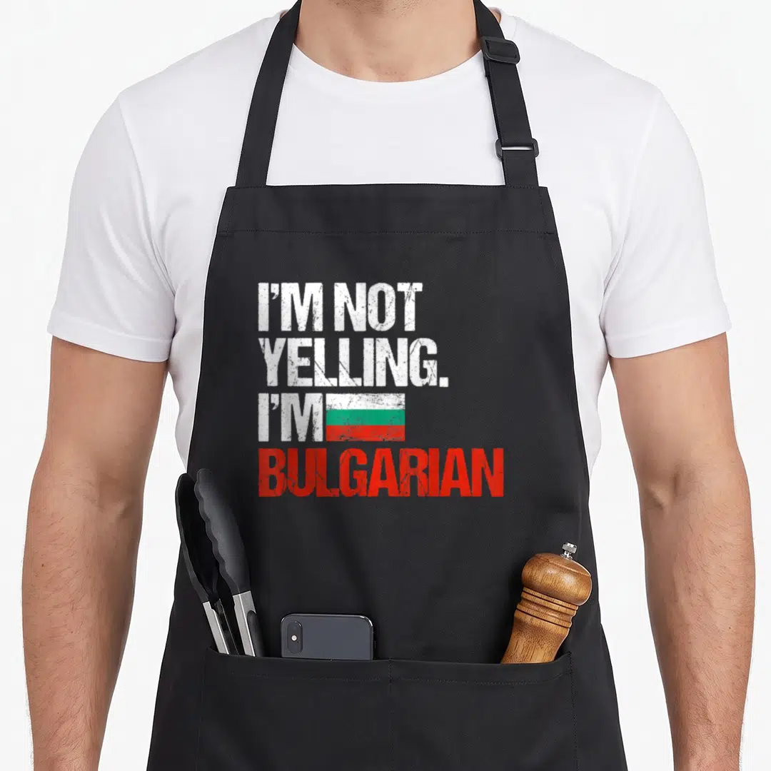 Yelling bulgarian apron - Stacked distressed text I'M NOT YELLING I'M BULGARIAN with small flag graphic — shown on a black cotton canvas apron against a white background