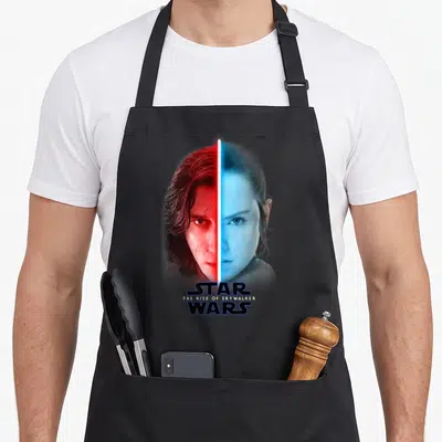 Rise split apron - Kylo Ren and Rey split faces red blue lightsaber Star Wars The Rise of Skywalker text — shown on a black cotton canvas apron against a white background