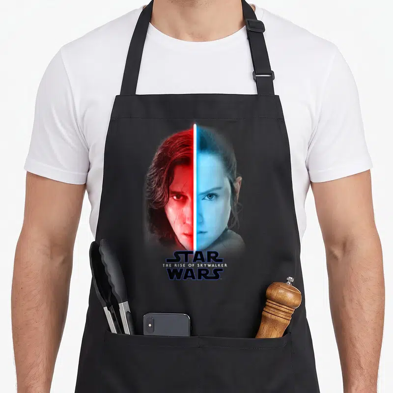 Rise split apron - Kylo Ren and Rey split faces red blue lightsaber Star Wars The Rise of Skywalker text — shown on a black cotton canvas apron against a white background
