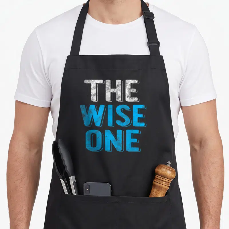 Wise passover apron - Stacked white and blue text reading THE WISE ONE — shown on a black cotton canvas apron against a white background