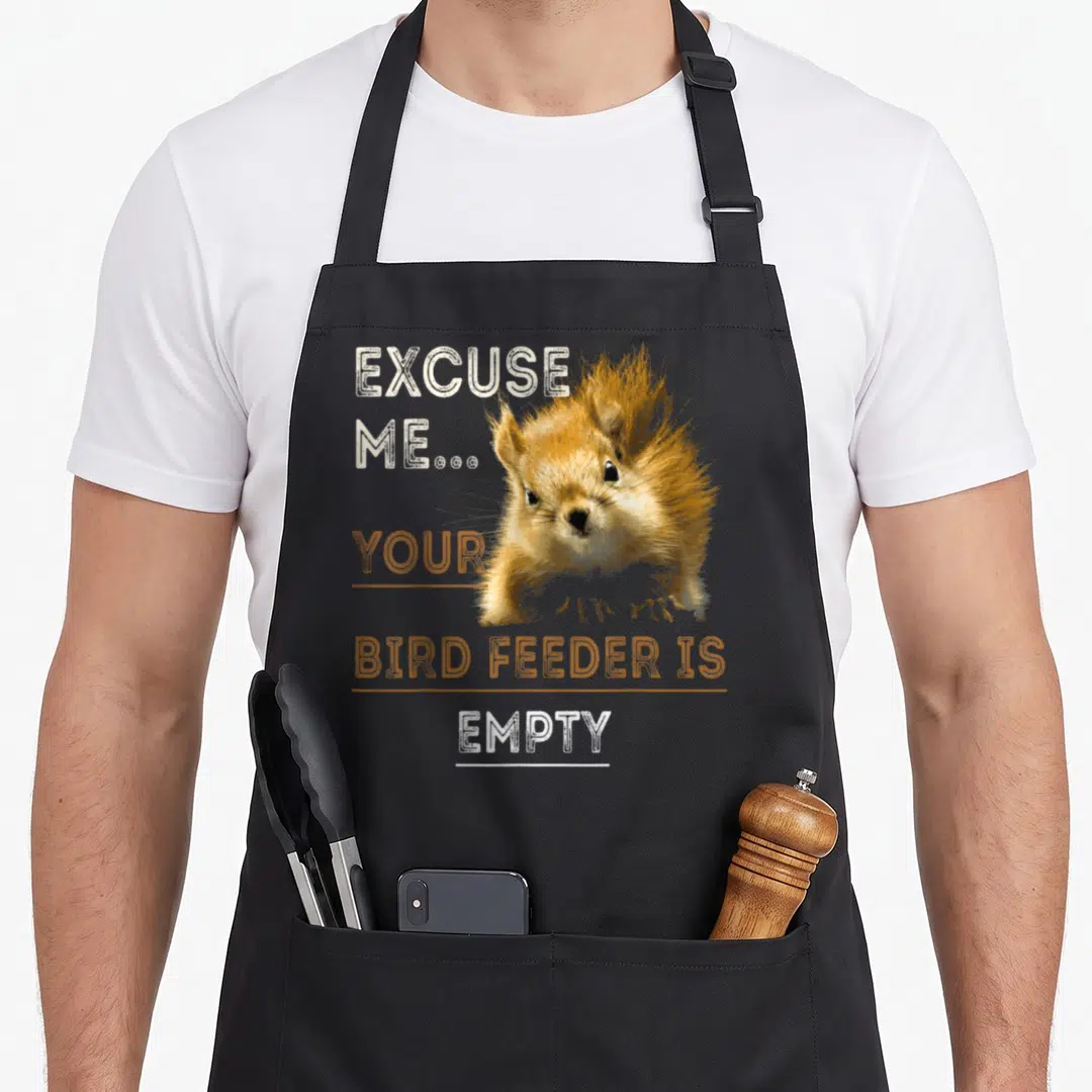 Bird squirrel aprons - Squirrel photo with text Excuse Me Your Bird Feeder Is Empty in orange and white — shown on a black cotton canvas apron against a white background