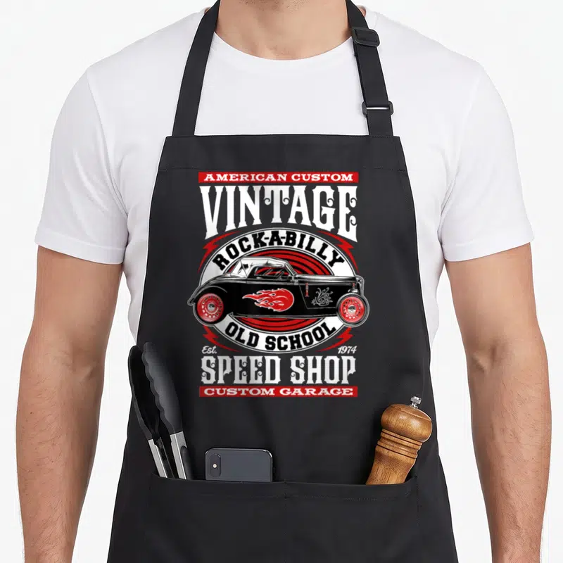 Rod rockabilly apron - Vintage hot rod car illustration with red flame details and speed shop typography — shown on a black cotton canvas apron against a white background