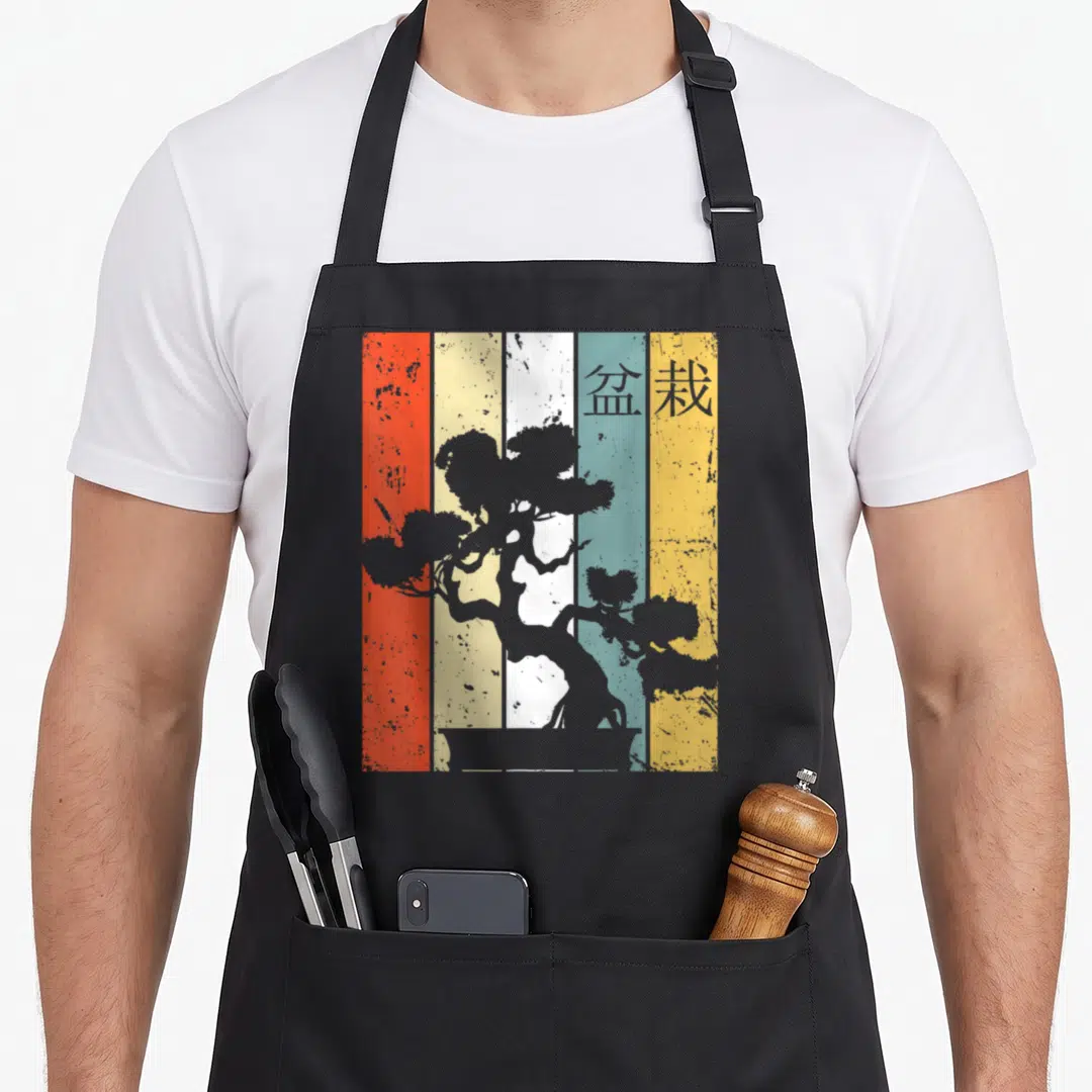 Funny bonsai tree apron - Grey bonsai silhouette over five vertical stripes of red, yellow, white, blue, and grey — shown on a black cotton canvas apron against a white background