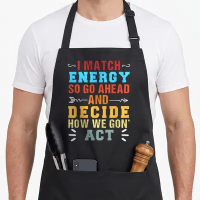Energy act apron - Stacked colorful text I MATCH ENERGY SO GO AHEAD AND DECIDE HOW WE GON' ACT with swirls arrows — shown on a black cotton canvas apron against a white background