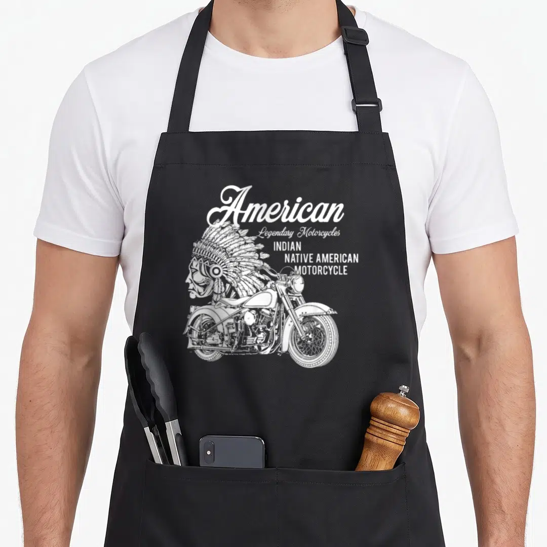 Motorcycle native american apron - White line art of motorcycle and headdress with stacked American text — shown on a black cotton canvas apron against a white background