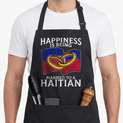 Haiti heritage aprons - Waving blue red flag with two gold interlocking rings and distressed white text — shown on a black cotton canvas apron against a white background