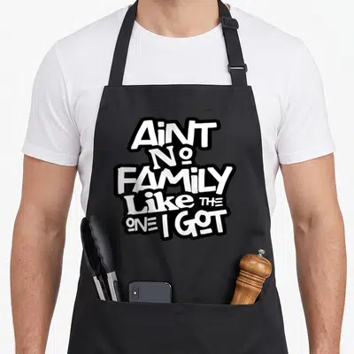 Retro family aprons - White AIN'T NO FAMILY LIKE THE ONE I GOT text on black background — shown on a black cotton canvas apron against a white background
