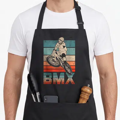 Bmx fan bike apron - Retro BMX rider illustration over teal beige and orange horizontal stripes with matching striped — shown on a black cotton canvas apron against a white background
