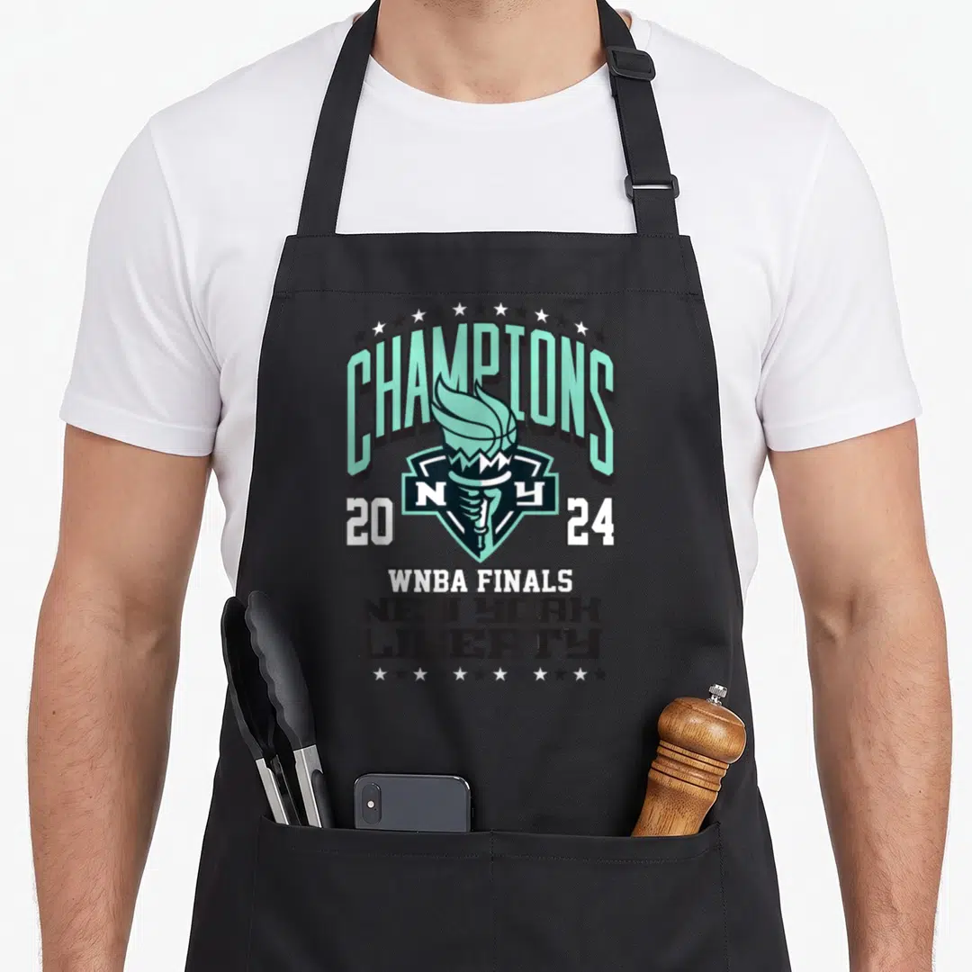 Championship new york apron - Mint green CHAMPIONS text arching over a torch and shield with WNBA Finals stacked below — shown on a black cotton canvas apron against a white background