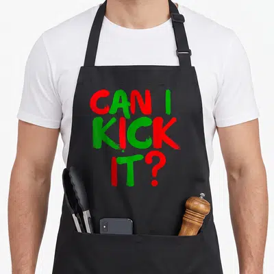 Kick hip aprons - Stacked red and green brushstroke text reading CAN I KICK IT — shown on a black cotton canvas apron against a white background