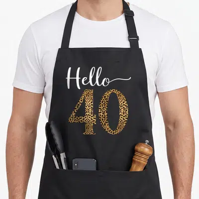 40th leopard print apron - Hello 40 text with leopard print number 40 and white script — shown on a black cotton canvas apron against a white background