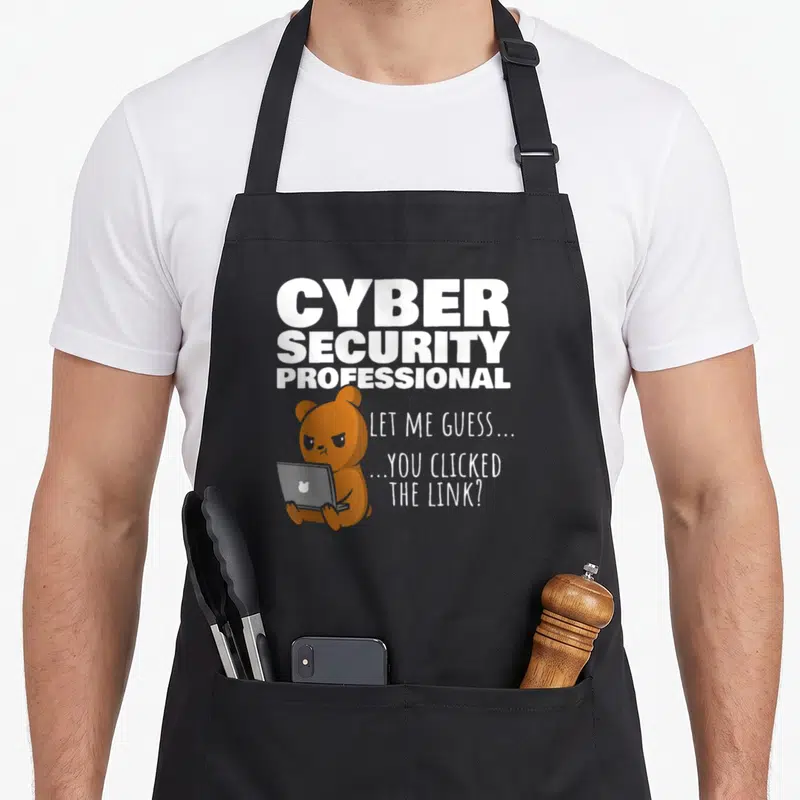 Clicked cybersecurity wife apron - Brown bear holding grey laptop under white CYBER SECURITY PROFESSIONAL text — shown on a black cotton canvas apron against a white background